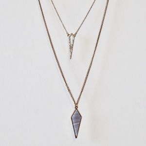 Gold necklace with a purple arrow pendant.